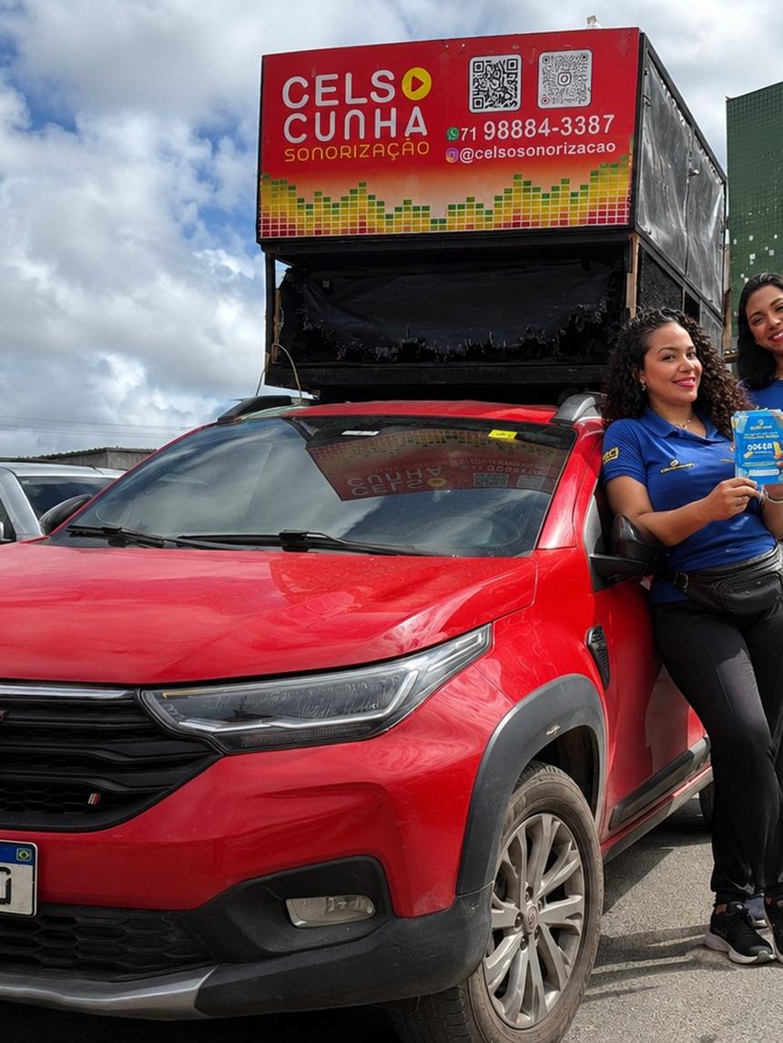 Promotoras com panfletos ao lado do carro de som